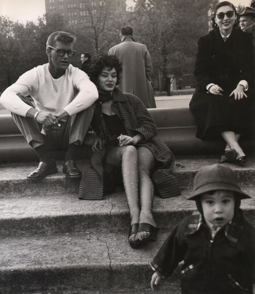 21. Weegee, Washington Square Park, c. 1955. A couple, a woman, and a toddler lounge on a set of stone steps.