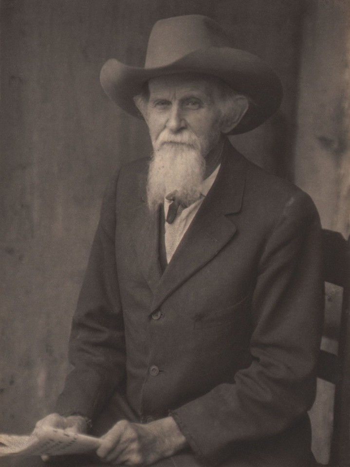 Doris Ulmann, Untitled (Gentleman), ​1928&ndash;1934. Bearded man seated in a wooden chair holding paper in his lap and looking to camera.