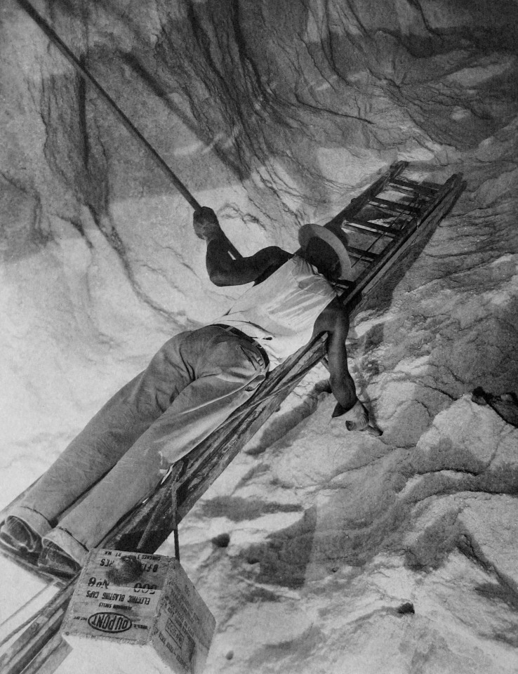 Harold Haliday Costain, Charging the Cliff with Dynamite, Avery Island, Louisiana, 1934. A man on a ladder occupies the frame diagonally.