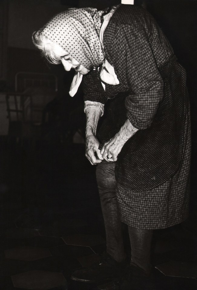 34. Mario Giacomelli, Verr&agrave; la morte e avr&agrave; i tuoi occhi, 1966&ndash;1968. High contrast image. A hunched old woman looks and bends toward the lower left of the frame.