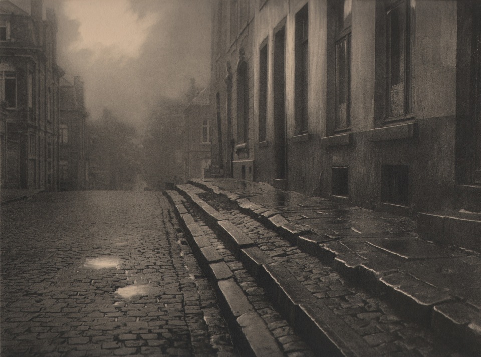 09. L&eacute;onard Misonne, [title illegible], c. 1930. Wet, cobbled, residential street and steps in soft light. Sepia-toned print.