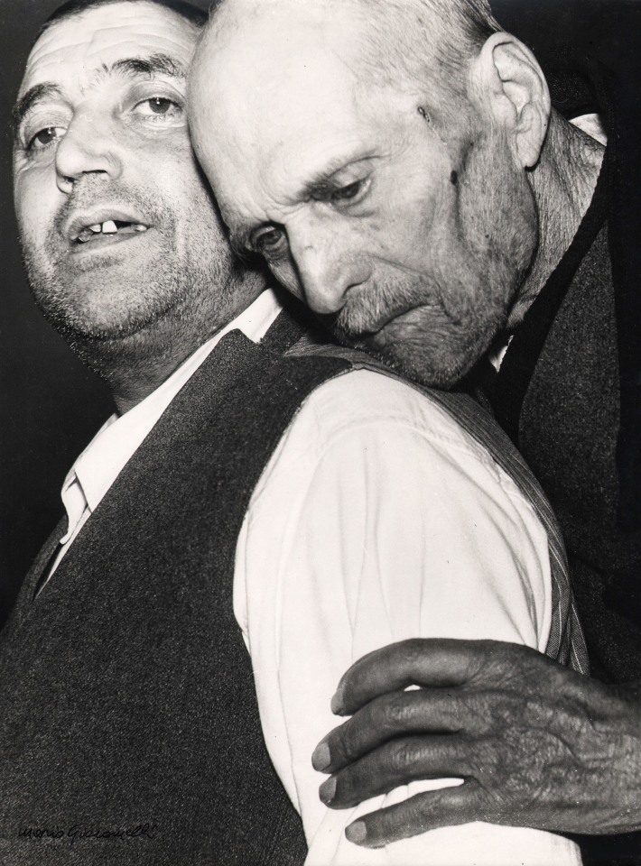 09. Mario Giacomelli, Verr&agrave; la morte e avr&agrave; i tuoi occhi, 1966&ndash;1968. High contrast image. One man leans his head against another's shoulder from behind, both faces turned towards the camera.