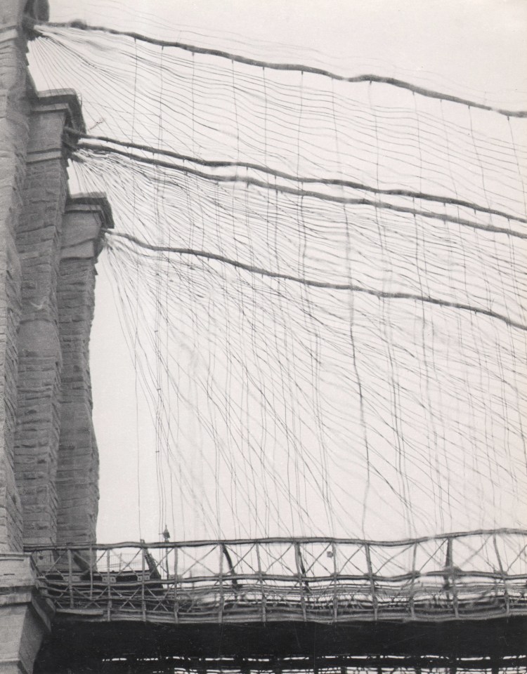 27. David Attie, Brooklyn Bridge, ​c. 1958. Distorted image of a portion of the Brooklyn Bridge from a low perspective. Most of the frame is filled with distorted, wavy cables.