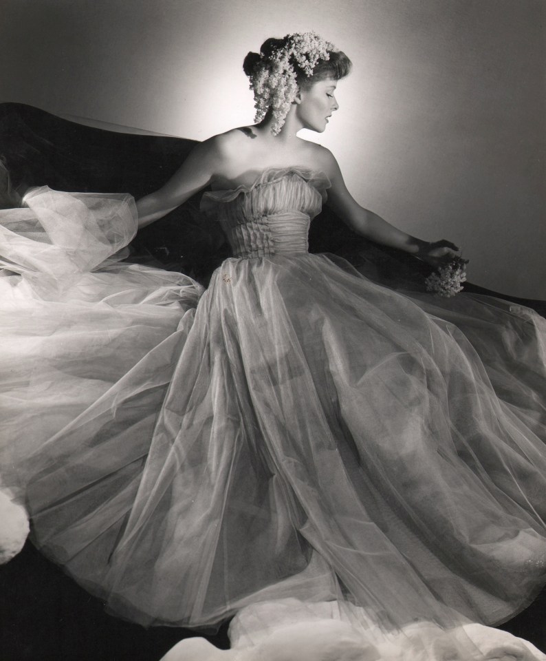 George Platt Lynes, Katharine Hepburn, ​c. 1946. Actress poses with flowing tulle gown and flowers in her hair, face turned to the right.