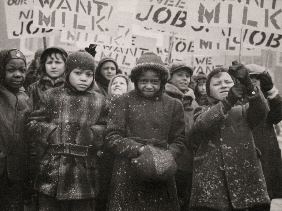 Gordon Coster, Untitled, ​c. 1938. Crowd of children in winter coats holding signs above their heads. Signs are in partial view, but the words &quot;MILK&quot; AND &quot;JOB&quot; can be seen.