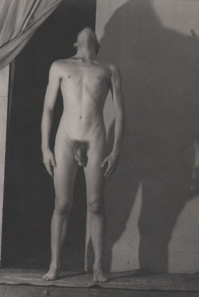 PaJaMa (Jared French), John Butler, ​1943. Nude male figure with head turned upward, a wide shadow cast on the wall behind him.