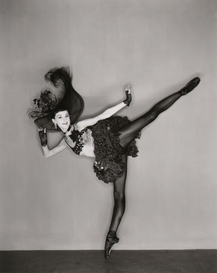 George Platt Lynes, Tanaquil LeClercq, Western Symphony, c. 1956. Dancer in black on pointe shoes kicks outward to the right.