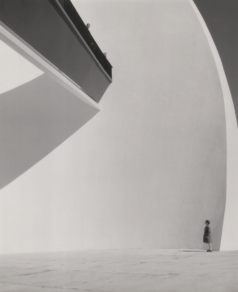 Aldo Spadoni, La Bianca Parete, ​1954. A young child in profile stands in the lower left of the frame. A man looks over a balcony on the upper left.