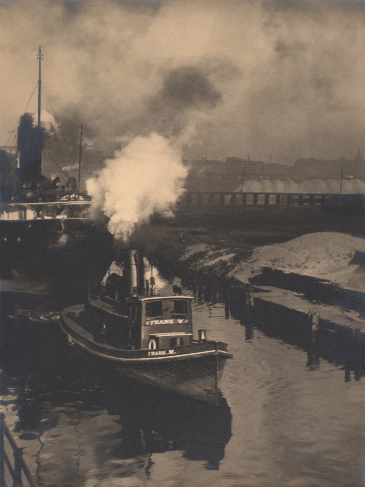 18. Margaret Bourke-White, 'Frank W.' on the Cuyahoga, c. 1929. Steam boat marked &quot;Frank W&quot; floating on a river. A cloud of smoke rises above it.