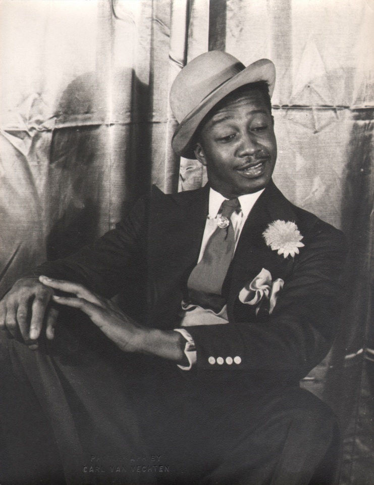 37. Carl Van Vechten, Avon Long as Sporting Life, Porgy &amp; Bess, 1942. Subject in a seated pose with legs crossed and hands on knee, looking down and to the right.