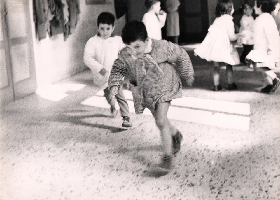 22. Renzo Tortelli, Piccolo Mondo, 1958&ndash;1959. High contrast image. Two boys running, blurred with motion, in the center of the frame. Other children play in the upper left background.