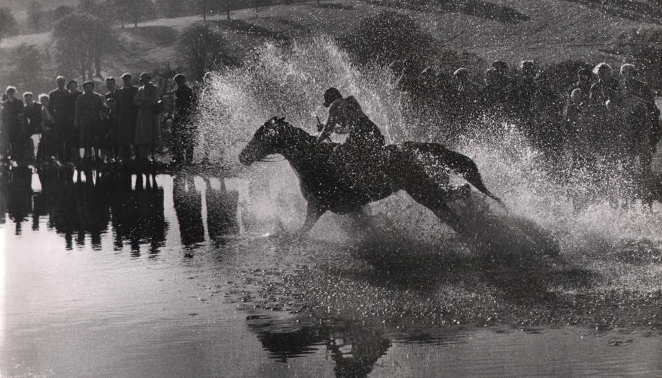 15. Graham Finlayson, Untitled, c. 1958&ndash;1966. Water splashes around a horse and rider moving right to left across the frame as a crowd watches in the midground.