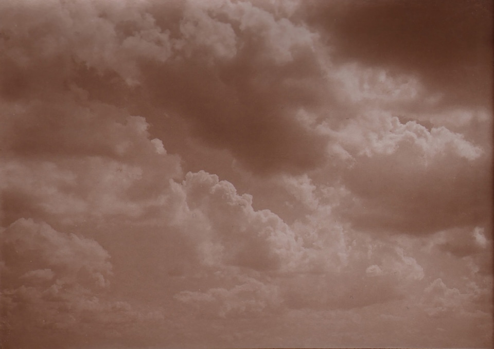 31. L&eacute;onard Misonne, Untitled, c. 1930. Cloud-filled sky. Sepia-toned print.