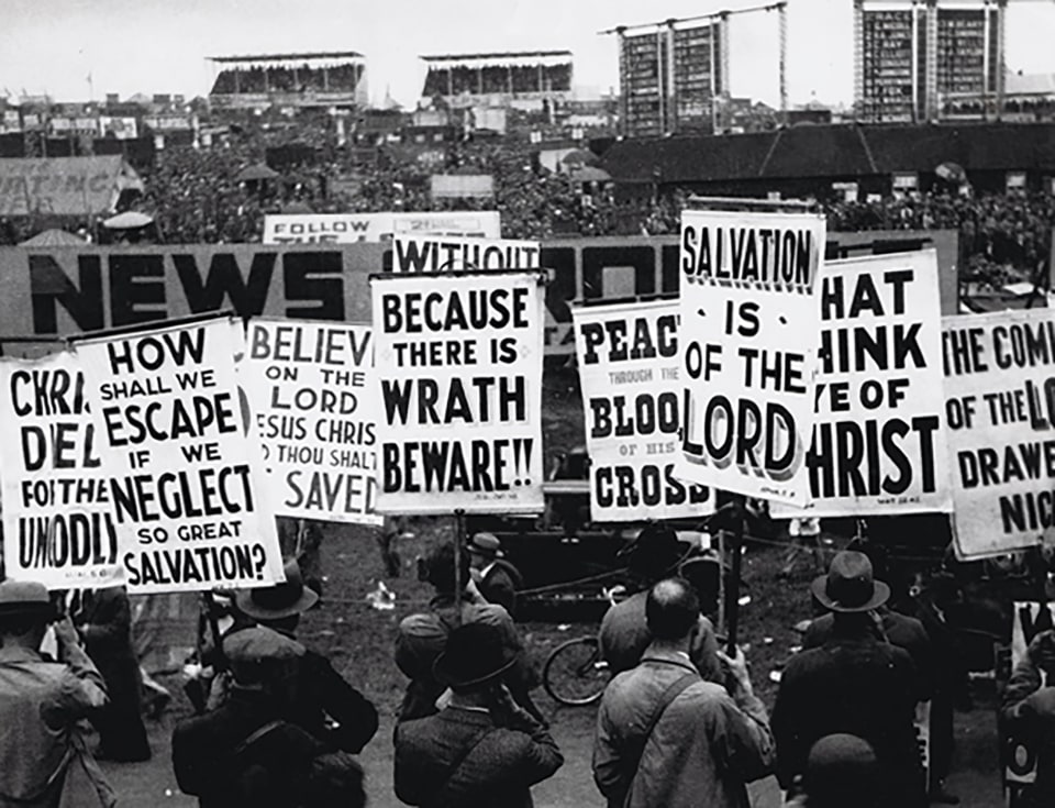 38. Bill Brandt, Religious Demonstration, Epsom Derby Day, ​c. 1933. Crowd from behind holding signs such as &quot;Because there is wrath beware!!&quot; and &quot;Salvation is of the lord&quot;