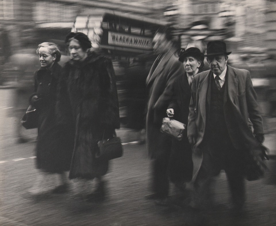 24. David Moore, 5P.M. Rush Hour - London, ​c. 1955. Five figures walking on a sidewalk, blurred with motion.