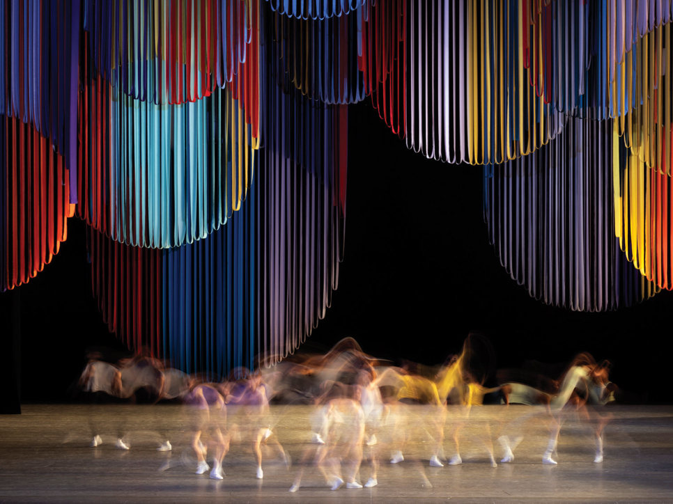 Dancers performing on a stage with hanging circular ribbons as a backdrop