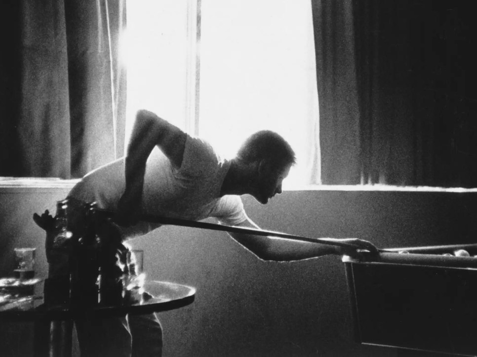 Black and white photo of a young man playing pool