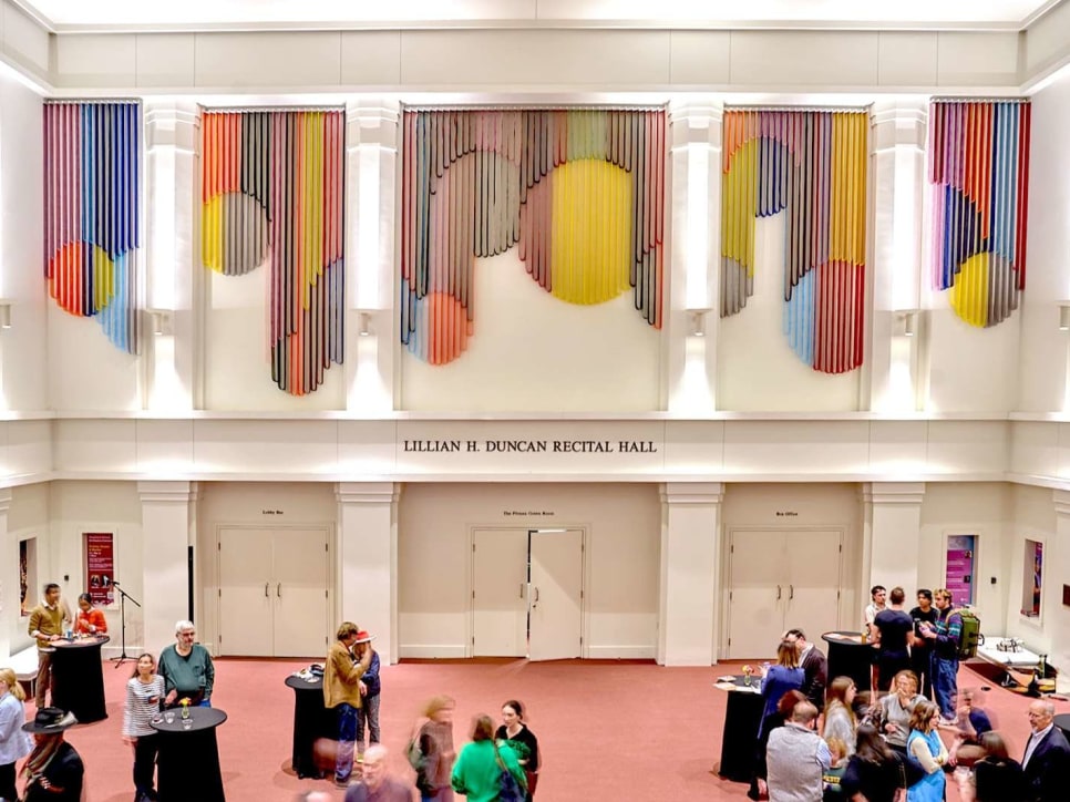 Art installation of multiple colored strips forming geometric shapes in a lobby of a recital hall