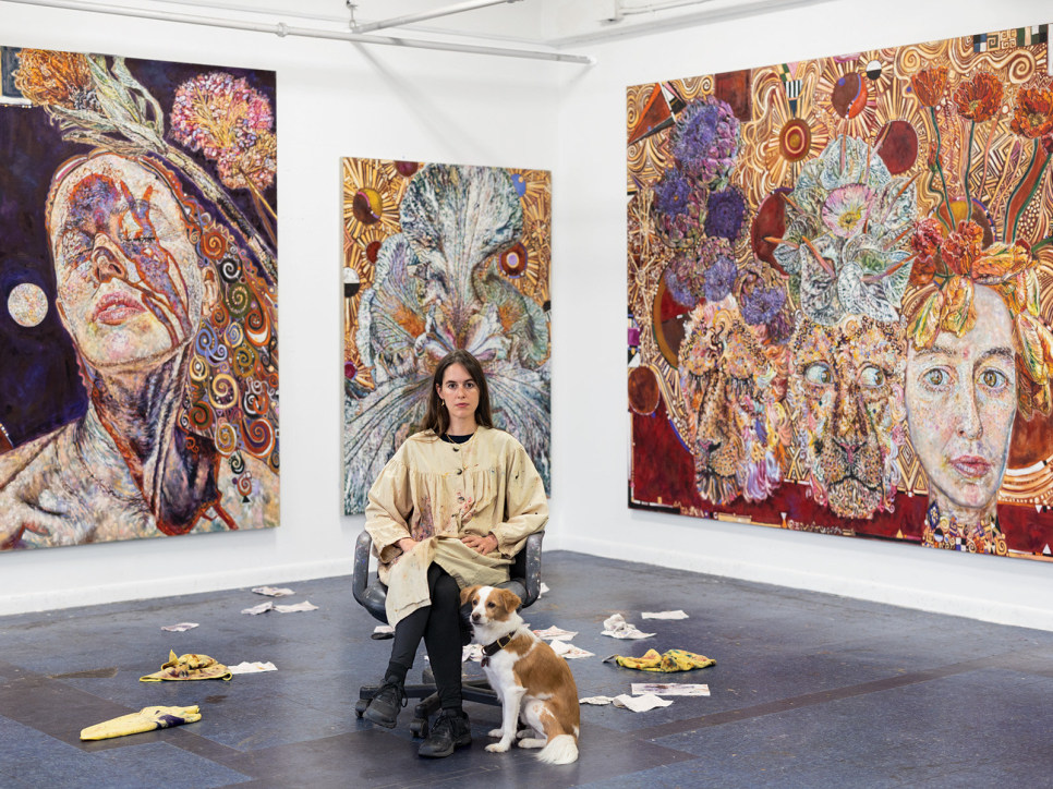 Constanza Schaffner seated in her studio in front of 3 figurative paintings