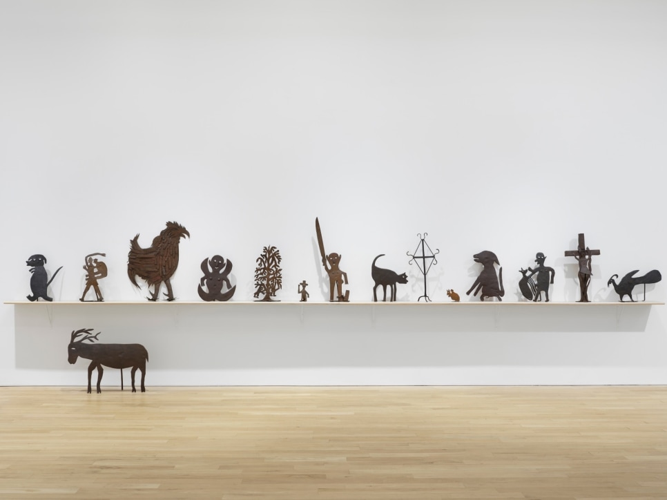 A set of metal sculptures depicting animals and human figures installed in an art gallery