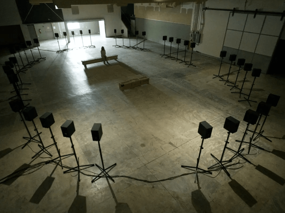 Sound installation in an empty warehouse with 40 speakers surrounding a central seating area