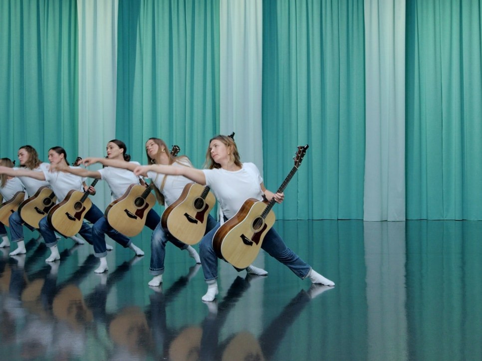 8 female dancers holding guitars