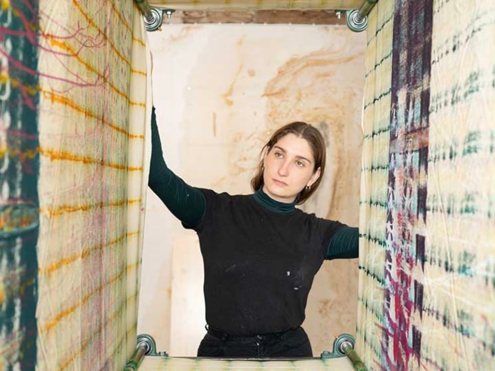 A female artist in her studio with abstract patterned painting