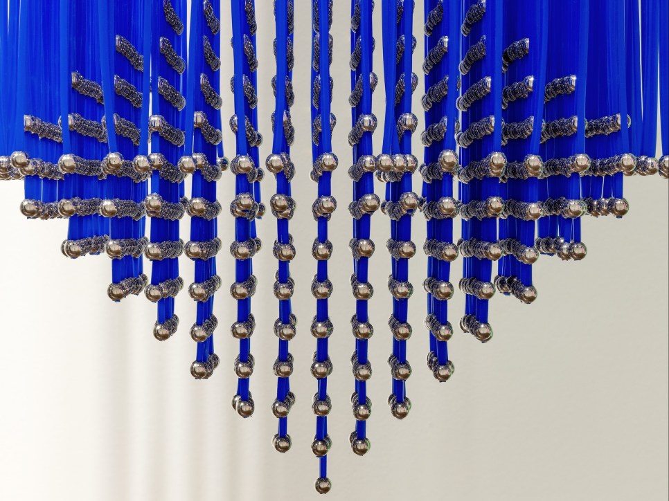 Hanging sculpture with metal balls attached to blue strips of plastic