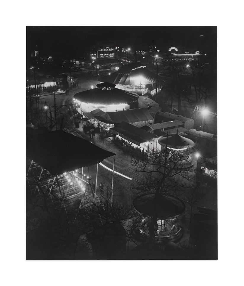 Black and white photographic by Brassaï featuring a birds-eye-view of a carnival scene 