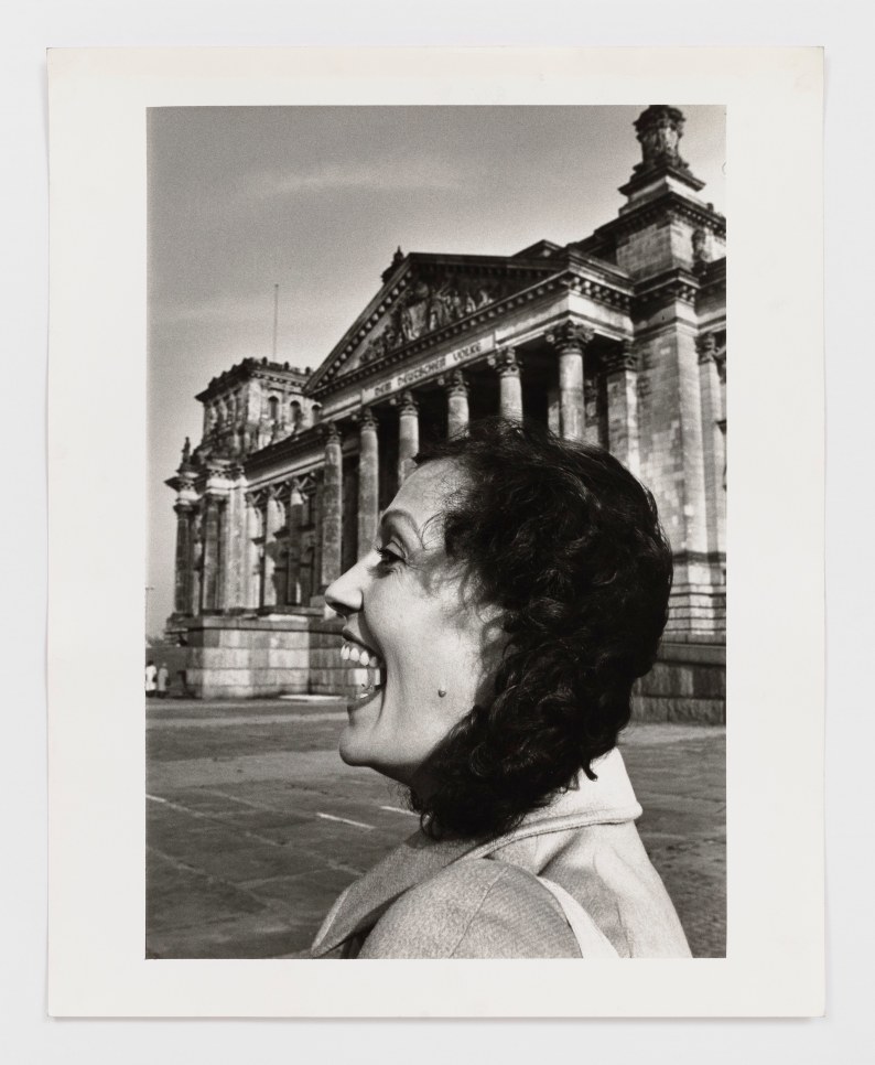 Black and white photographic print by Helmut Newton featuring the profile view of a woman laughing near the Reichstag