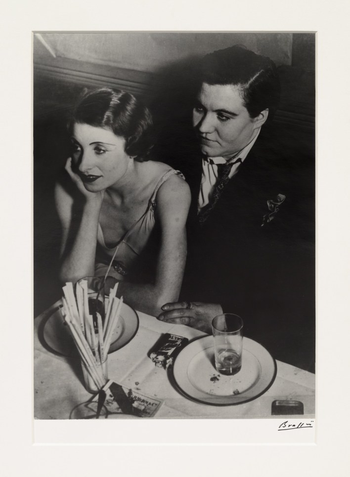 Black and white photographic by Brassaï featuring a couple sitting at a dinner table