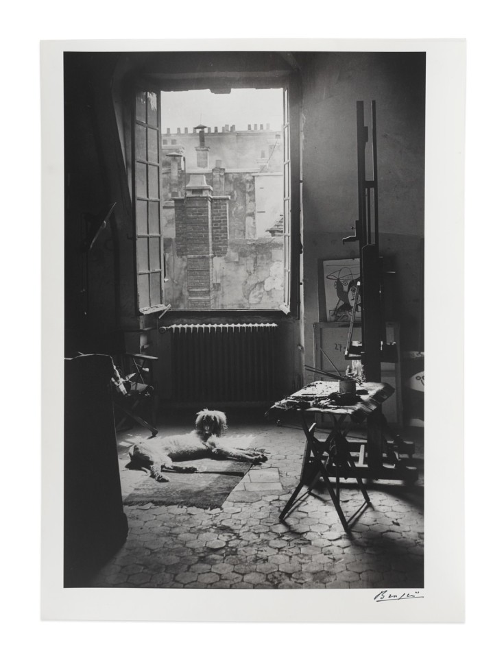 Black and white photographic by Brassaï featuring a dog laying down under a window in an art studio