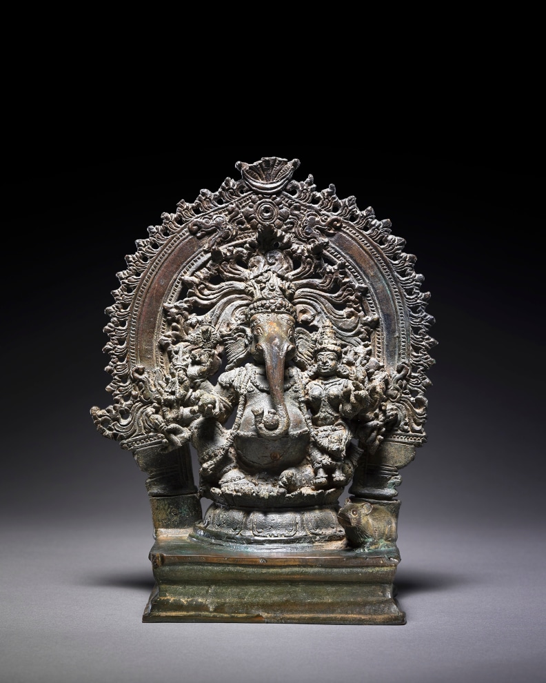 The corpulent elephant-headed divinity Ganesha is seated in rajalilsana on a lotus throne.